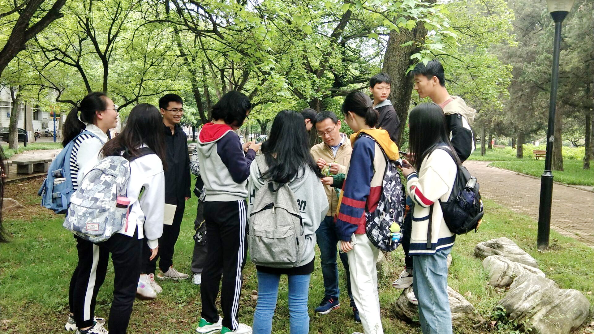 李刚老师在校园里带领同学们认识植物